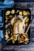 Garlic chicken with potatoes in a roasting tray (top view)