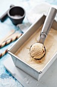 Salted caramel ice cream in a tub and on a scoop