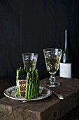 A sandwich cake with green asparagus served with white wine