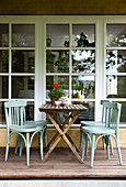 Bistro chairs and folding table on terrace in front of large window