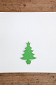 Christmas-tree silhouette cut out of green paper on white surface