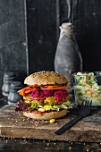 A spelt burger bun with coleslaw, beetroot, and sweet potato