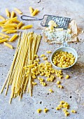 Various types of pasta next to parmesan