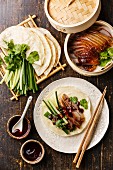Peking-Ente serviert mit Gemüse, Koriander, Pfannkuchen und Hoisinsauce (China)