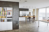 White built-in shelves framed by a coated wall and gas fire with views into an open-plan kitchen