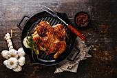Grilled fried roast Chicken Tabaka in frying pan on wooden background