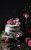 Naked cake decorated with roses on wooden table