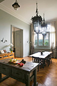 View past island counter into dining room with old ceiling lamps