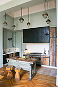 Stools in front of old workbench used as island counter in rustic kitchen