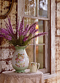 Strauß mit Blumen in nostalgischer Vase vor einer verwitterten Wand