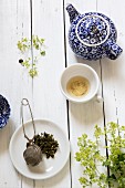 Stillleben mit blau-weisser Teekanne, leergetrunkener Teetasse und Teesieb