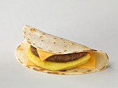 A tortilla with cheese, omelette and a meat patty