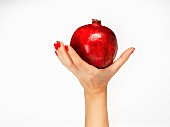 A woman's hand holding a pomegranate