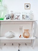 Vintage photos in glass vessels on wall-mounted shelf