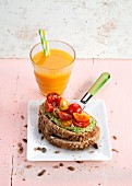 Carrot and fruit juice, and toasted bread with avocado cream and cherry tomatoes