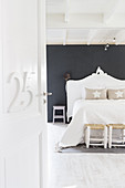 Number on open interior door with view into white bedroom with black wall