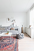 Alter Teppich und modernes graues Sofa im weißen Wohnzimmer
