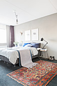 Oriental rug next to bed in bedroom with grey wall