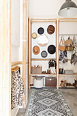 Patterned rug in font of simple coat rack made from cellar shelving