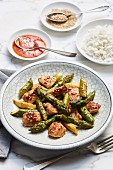 Fried green asparagus with chicken breasts in sweet and spicy sauce with rice and sesame seeds