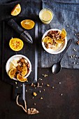 An orange smoothie bowl with crunchy muesli and coconut butter