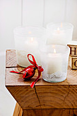 Three white lanterns with lace braids on a wooden stool