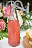 Pink lemonade in a glass bottle with a drinking straw