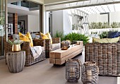 Wicker furniture and rustic coffee table made from untreated wooden beams on patio