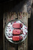 Homemade cherry and rose mangnums with a drak chocolate tip, on a dark wooden background