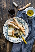 Grissinis mit Pecorino, Oliven, und Olivenöl serviert mit einem Glas Rotwein