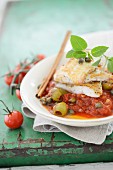 Fish fillets on tomatoes with green olives
