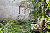 Old sofa in courtyard with Virginia creeper growing over garden wall
