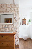 Waschbecken in alter Kommode an der Raumteilerwand mit Steinen