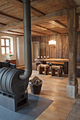Drum-shaped wood-burning stock in rustic parlour with wooden furniture