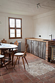 Farmhouse chairs around table in kitchen with terracotta floor tiles
