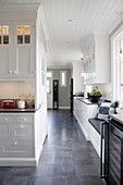 White panelled cabinets and grey floor in large, country-house kitchen