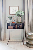 Vases of flowers on metal console table against grey wall