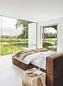 Leather bed in minimalist bedroom with view of landscape