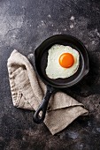 Fried egg on iron pan on dark background