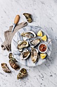 Open shucked Oysters with lemon and spicy sauce on white marble background