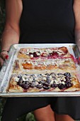 Three puff pastry pastries with cherries, apricots, and plums on a baking sheet