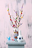 Twigs decorated with colourful pompoms in retro vase