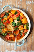 Chicken thights braised with sweet potatoes, spinach and tomatoes