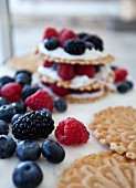Stacks of wafer cookies, icing and mixed berries with a white background