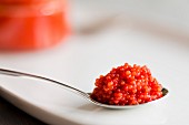 A teaspoon piled with lumpfish roe on a white background