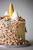 A bespoke made unicorn celebration cake made with multocoloured mane and golden horn