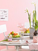 Gedeckter Tisch mit Salat, Wein und Frühlingsblumen zu Ostern