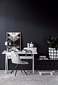 Grauer Stuhl und Schreibtisch vor schwarzer Wand