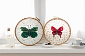Fabric embroidered with butterflies in embroidery frames on windowsill