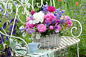 Basket with early-summer perennials arrangement on garden bench